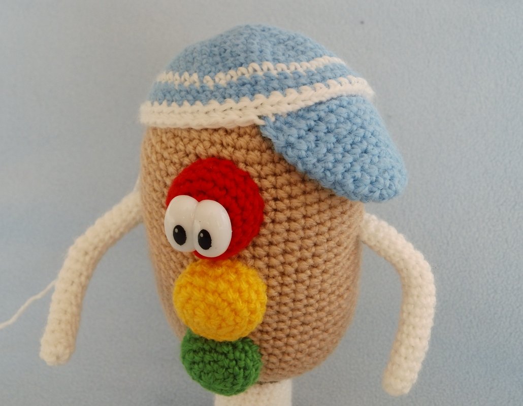 Farbenfrohes Amigurumi mit blau-weißer Mütze und gestapelten Häkelkreisen in Rot, Gelb und Grün