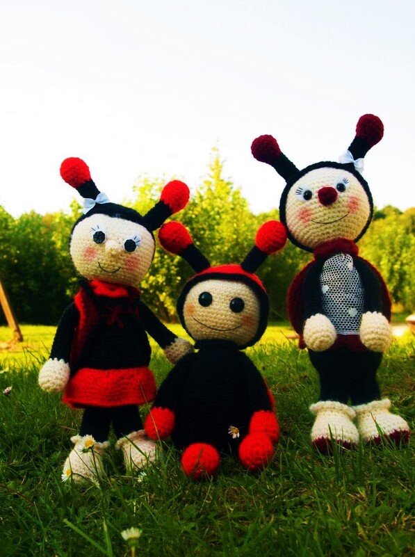 Drei gehäkelte Marienkäfer-Amigurumi in Rot und Schwarz auf Gras