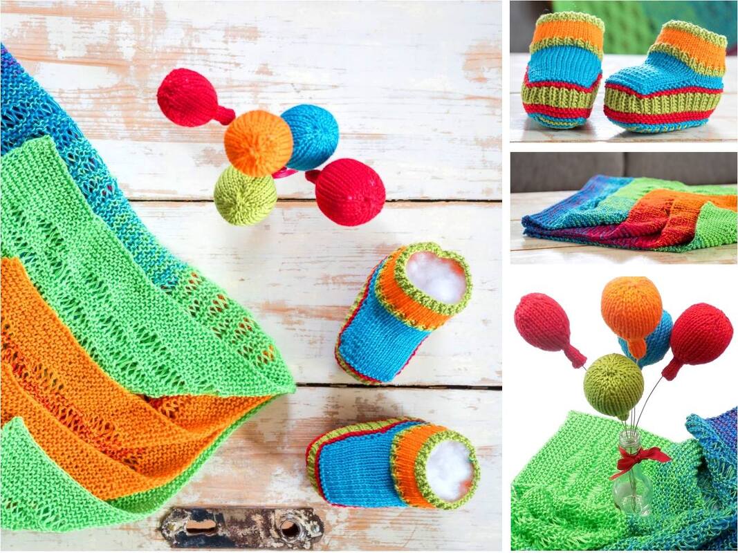 Bunte gestrickte Babydecke mit einem Paar Babyschuhen und mehreren gestrickten Kugeln auf hellem Holzhintergrund