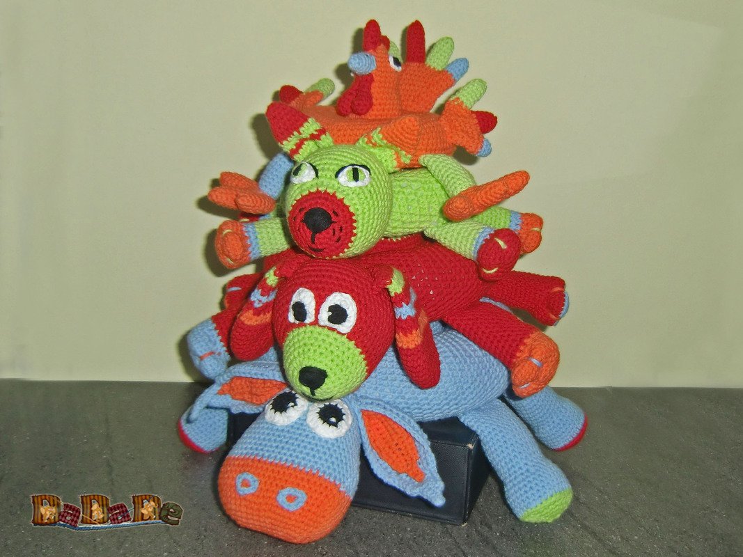 Stapel aus vier bunten, handgehäkelten Amigurumi-Tieren: Esel, zwei Hunde und Hahn.