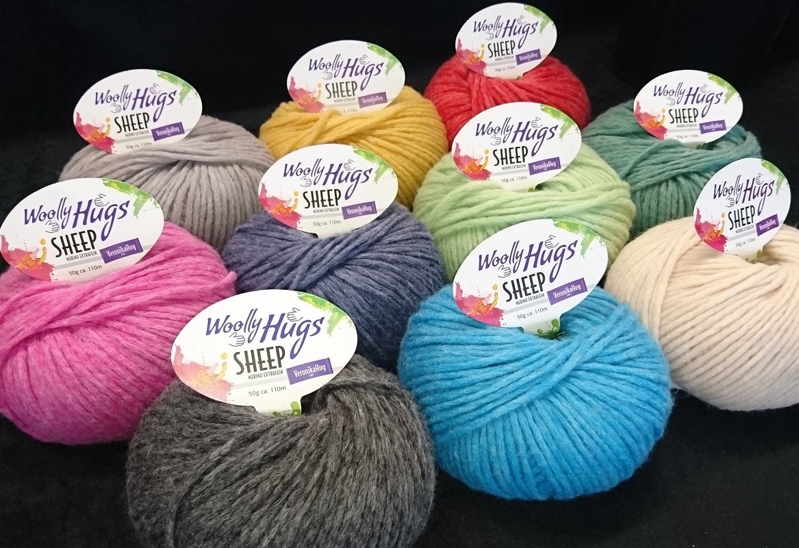 Elf bunte Wollknäuel mit Etiketten auf schwarzem Hintergrund