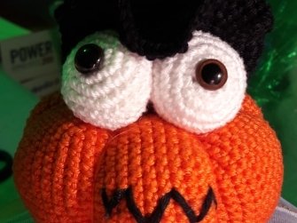 Skurriler gehäkelter Kürbis mit übergroßen weißen Augen und gezacktem schwarzem Grinsen