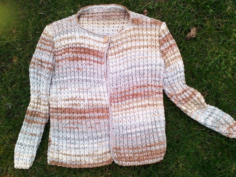 Melange-Cardigan für Damen in Creme- und Brauntönen mit Rippenstruktur und einem Knopf, liegend auf Gras
