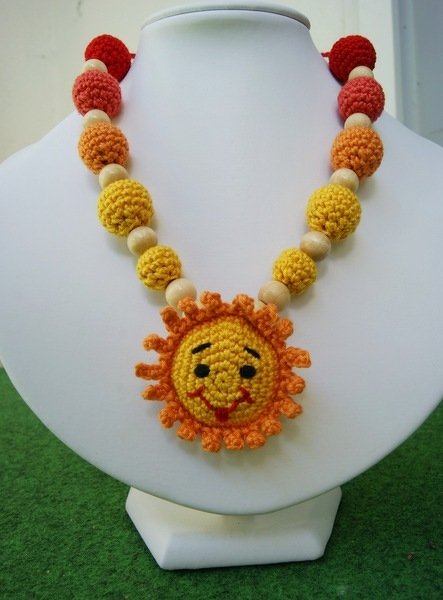 Gehäkelte Kinderkette mit Sonnenanhänger, Garn- und Holzperlen auf Schmuckbüste