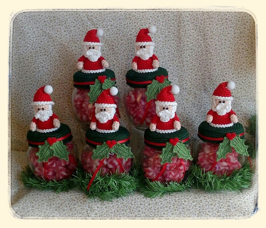 Gehäkelte Weihnachtsmann-Figuren als Deckel auf Gläsern, komplett mit Bart, Bommelmütze und Stechpalmen-Applikationen.