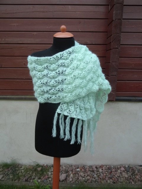 Hellgrüner gestrickter Schal mit Ajourmuster und langen Fransen auf einer schwarzen Schaufensterpuppe