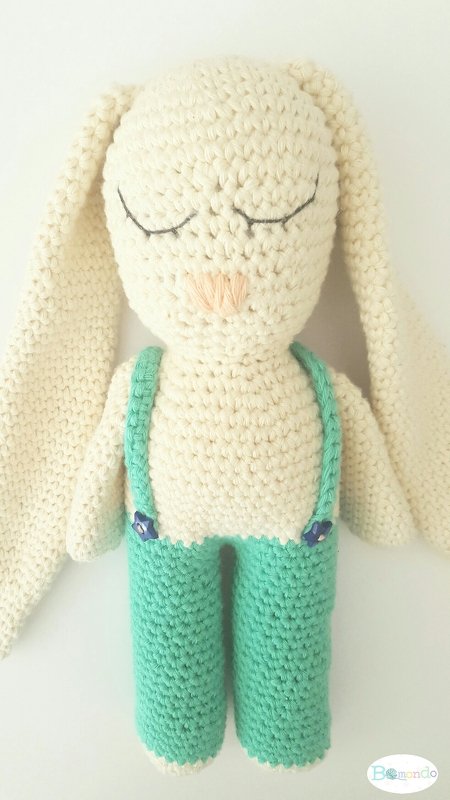 Gehäkelter cremefarbener Amigurumi‑Hase mit langen Ohren und mintgrüner Latzhose