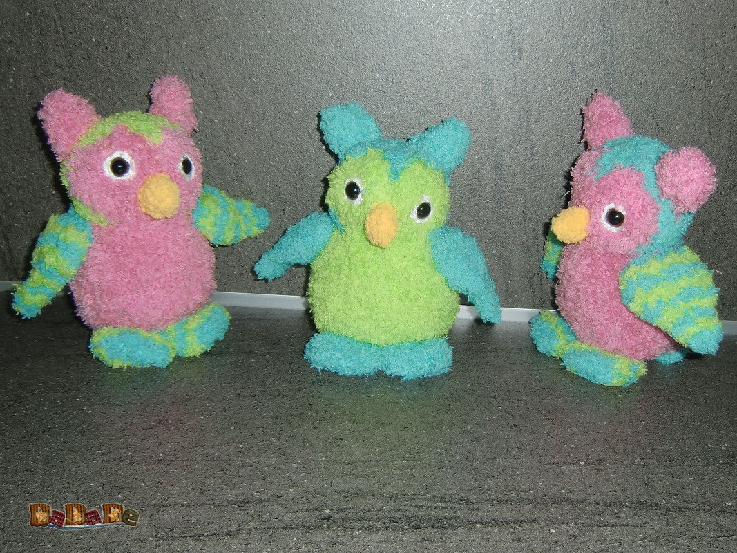 Drei gehäkelte Amigurumi-Eulen in Pastellfarben, frontal