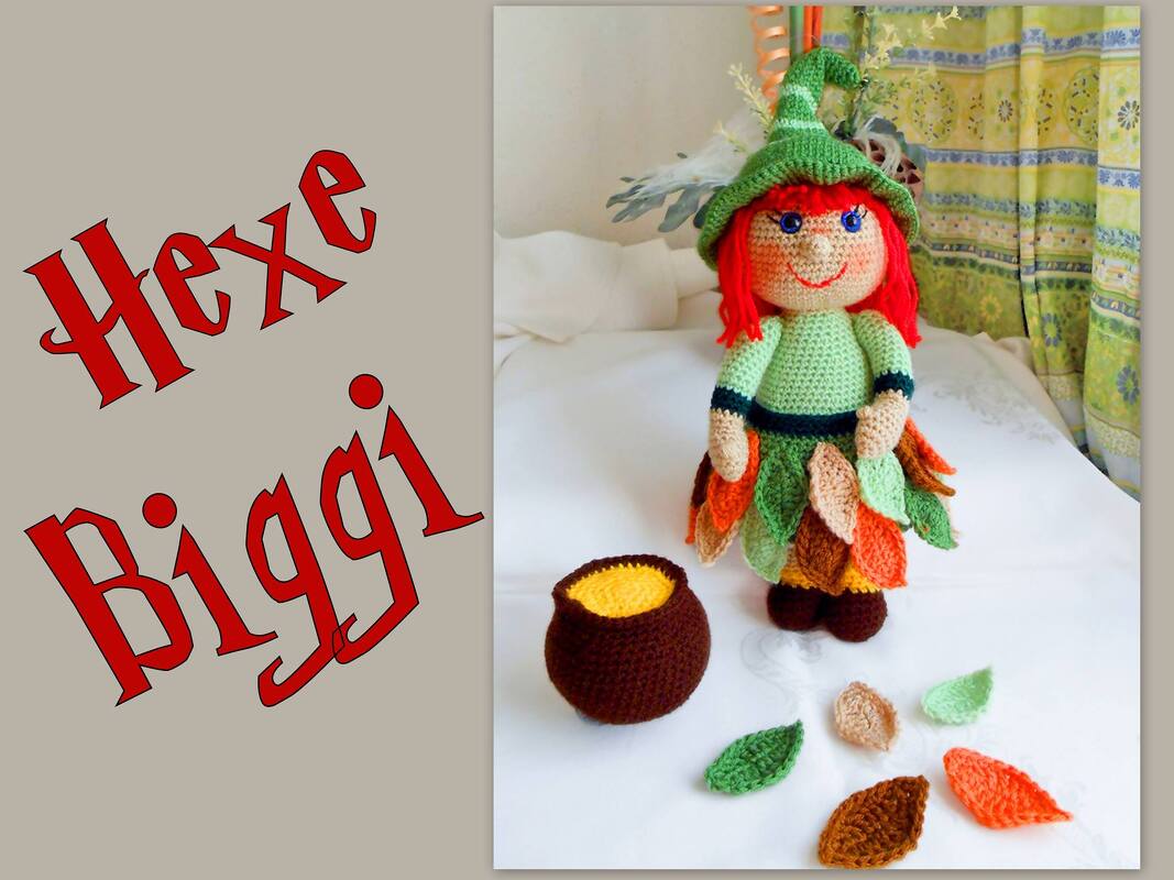 Gehäkelte Hexe mit rotem Haar, grüner Mütze und Blätterrock neben braunem Kessel und losen Blättern