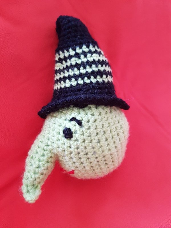 Gehäkelter Amigurumi-Kopf hellgrün mit langer Nase und schwarz-weiß gestreiftem Hut