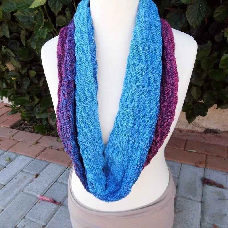 Blau-lila gestrickter Loop-Schal auf Schaufensterpuppe vor Laub