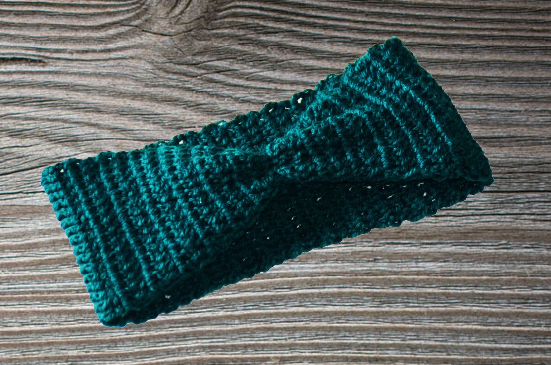 Gehäkeltes dunkelgrünes Stirnband mit Twist-Knoten und Rippenstruktur auf Holzhintergrund
