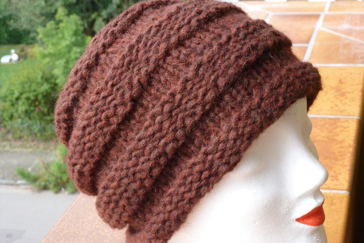 Dunkelbraune, locker gestrickte Mütze mit Rippenstruktur auf weißem Schaufensterkopf