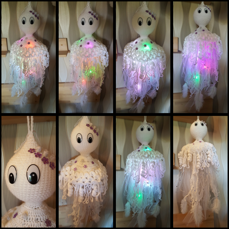 Mehrere Ansichten eines weißen gehäkelten Geistes mit Augen, lila Details, Federn und bunten LED-Lichtern.