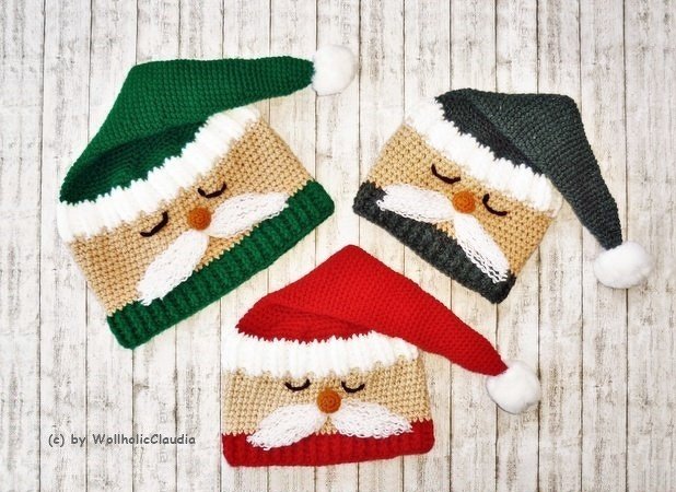 Drei gehäkelte Nikolausmützen in Rot, Grün und Anthrazit mit weißen Bommeln auf hellem Holzhintergrund