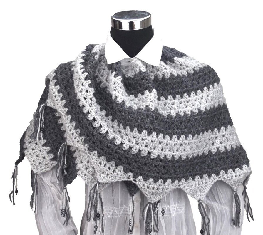 Gehäkelter dreieckiger Drachenschwanz-Schal in hell- und dunkelgrauen Streifen mit Fransen und Perlen auf einer Büste
