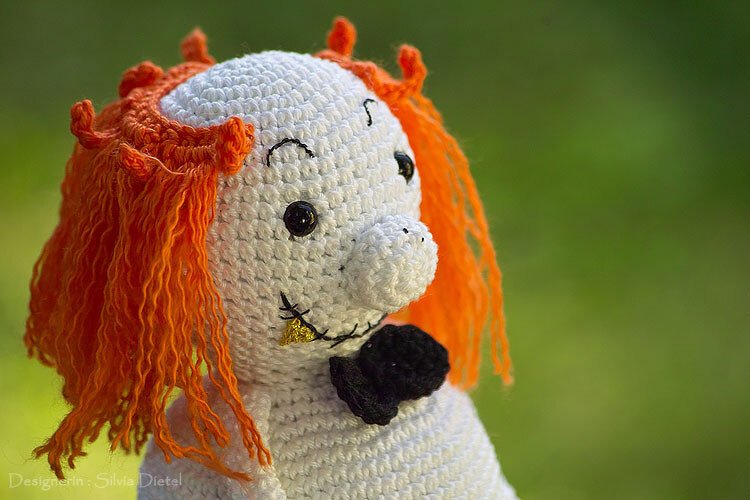 Gehäkelter weißer Geist mit orangefarbener Mähne und schwarzer Schleife