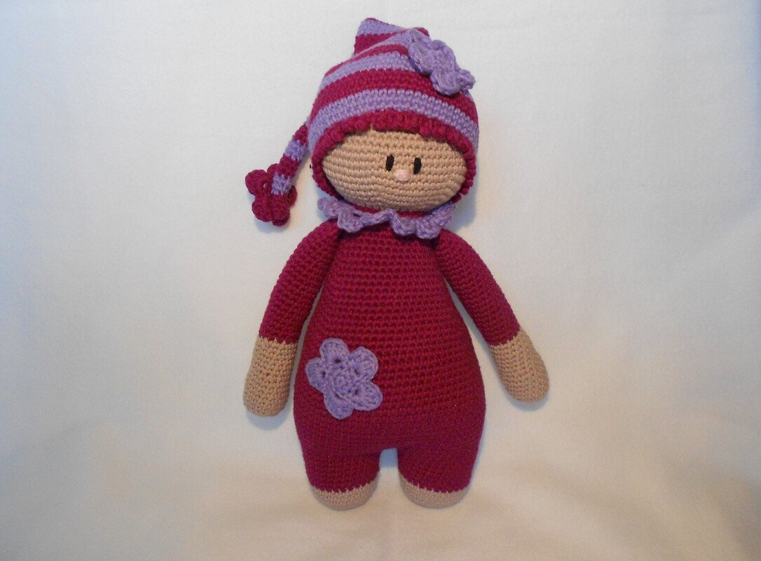 Gehäkelte Amigurumi-Puppe in Pink und Lila mit gestreifter Zipfelmütze und Blütenverzierung