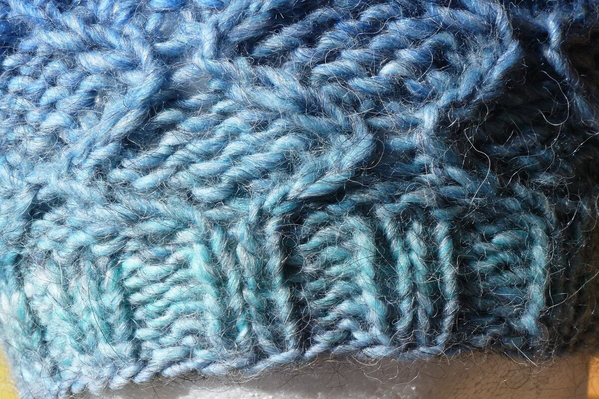 Nahaufnahme Strickdetail Zopfmuster und Rippenbündchen in Blau