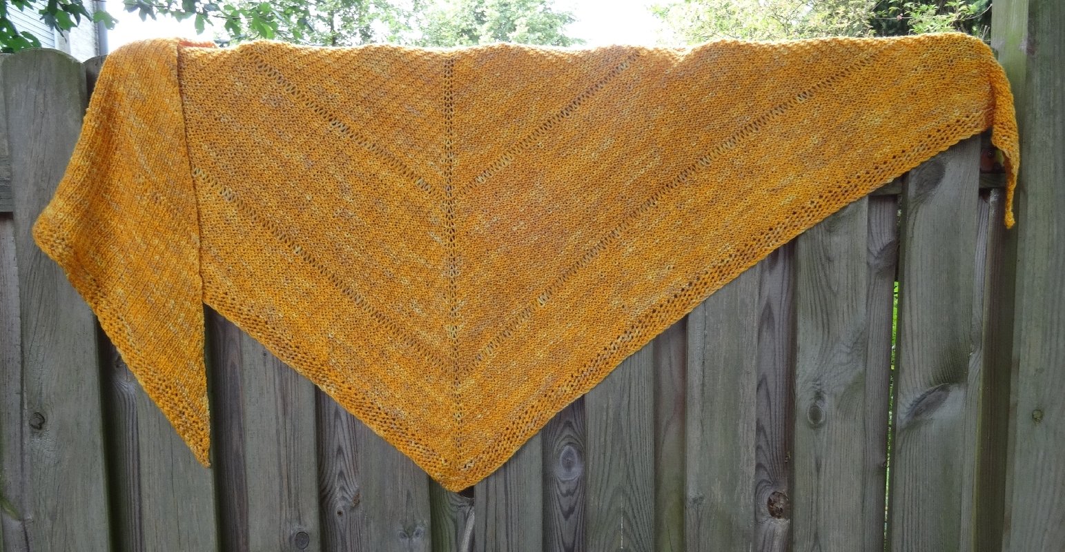 Senfgelbes gestricktes Dreieckstuch mit Lochreihen über einem Holzzaun