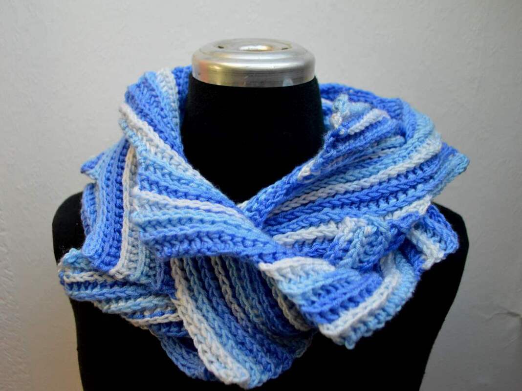 Gehäkelter Loop-Schal in Blau und Weiß, gestreift, auf einem schwarzen Mannequin.