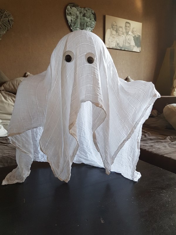 DIY-Geist aus drapiertem weißem Stoff mit zwei runden Augen auf einem Tisch