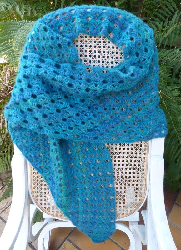 Petrolfarbenes gehäkeltes Dreieckstuch mit Ajourmuster auf Rattanstuhl drapiert