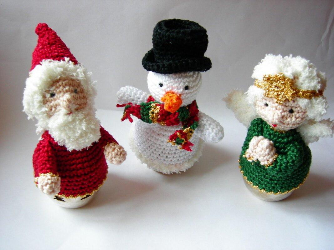 Drei gehäkelte Weihnachtsfiguren: Weihnachtsmann, Schneemann und Engel.