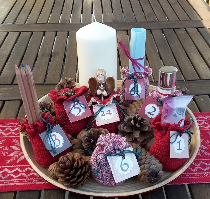 Tisch-Adventskalender mit nummerierten gehäkelten Säckchen, Kerze und Tannenzapfen