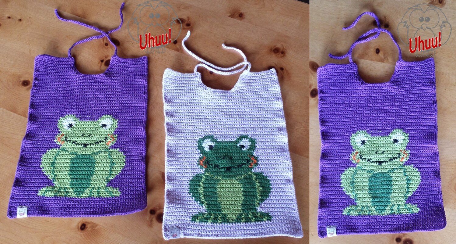 Drei gehäkelte Lätzchen mit Froschmotiv: zwei lila mit hellgrünem Frosch, eines hellviolett mit dunkelgrünem Frosch; alle mit Bindebändern.