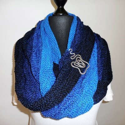 Gestrickter Loop-Schal in Blauverlauf auf Büste mit Metall-Anstecknadel