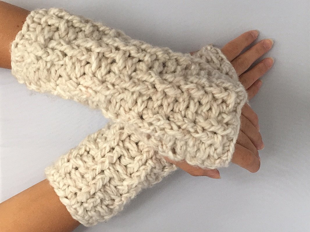 Cremefarbene, grob gehäkelte fingerlose Armstulpen an Händen