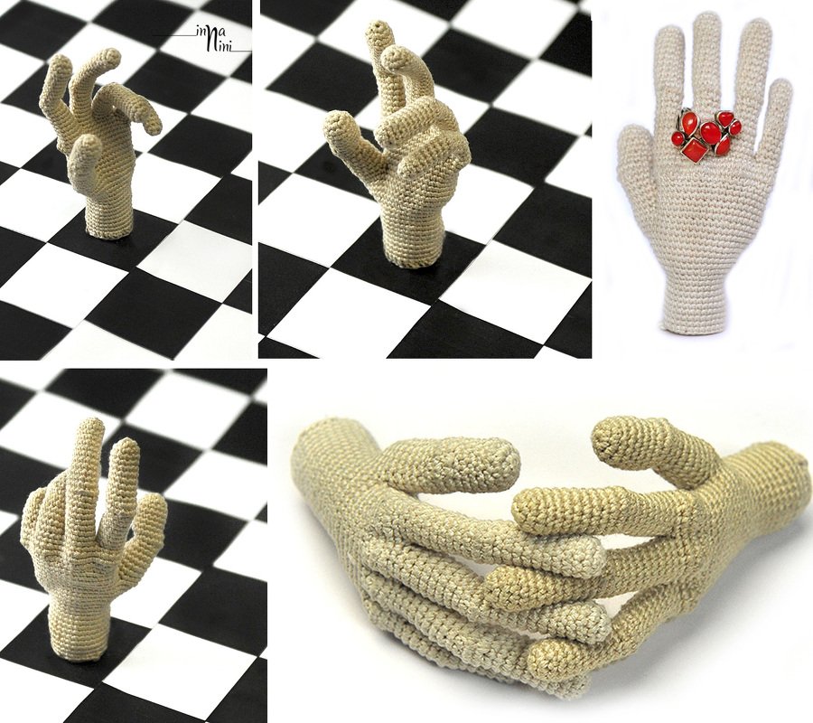 Gehäkelte Hände in verschiedenen Posen vor Schachbretthintergrund, eine mit rotem Schmuck