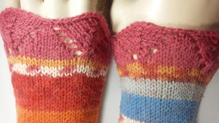 Zwei gestrickte Armstulpen mit bunten Streifen und zartem Ajourabschluss am oberen Rand.