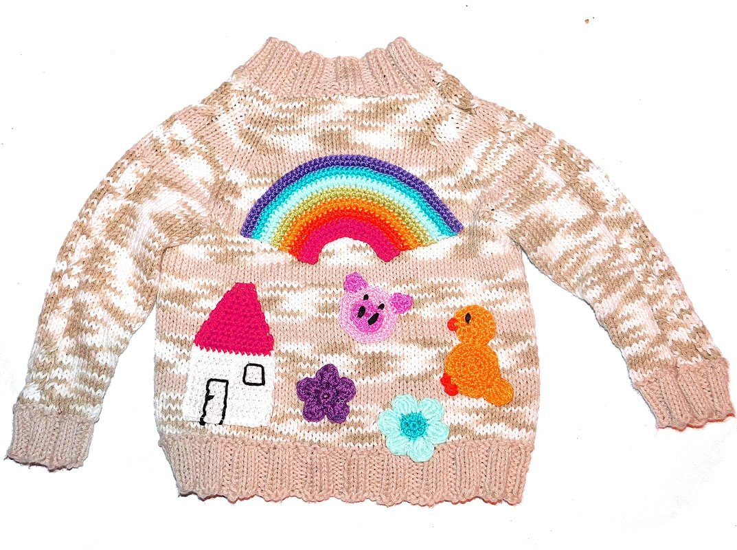 Beige-weißer gestrickter Kinderpullover mit bunten Applikationen: Regenbogen, Haus, Schwein, Ente und Blumen
