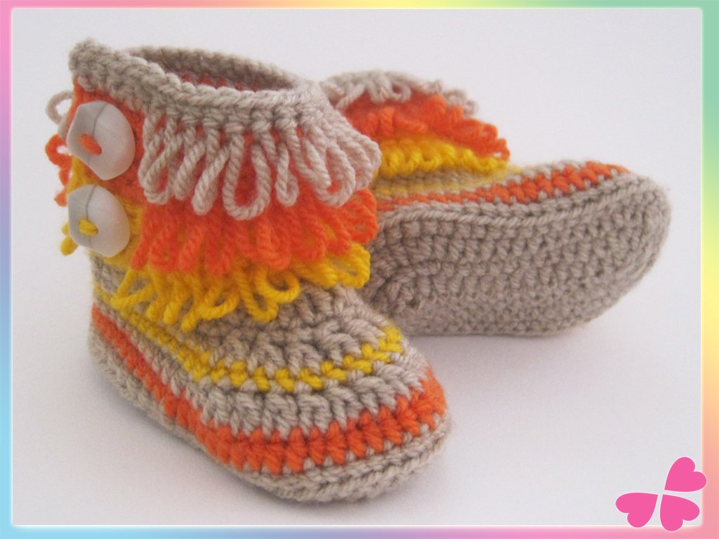Gehäkelte Babyschuhe in Beige mit orange-gelben Fransen und weißen Knöpfen