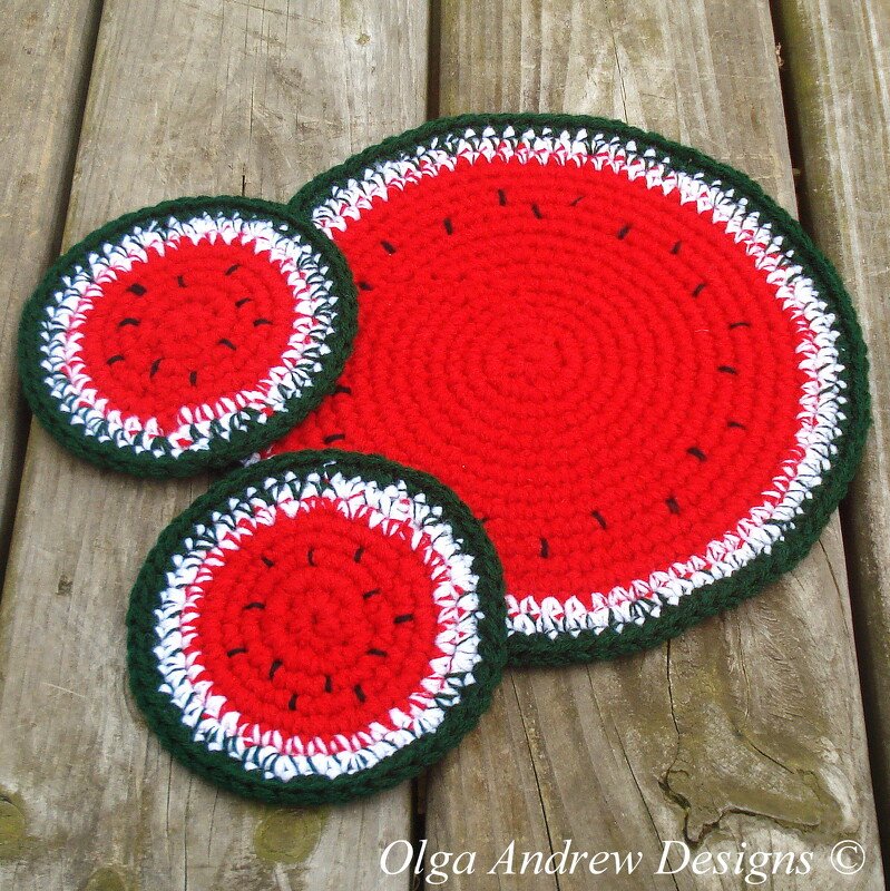 Two small round crocheted coasters and one larger crocheted trivet, designed as watermelon slices with red, white, and dark green colors, displayed on a wooden surface.