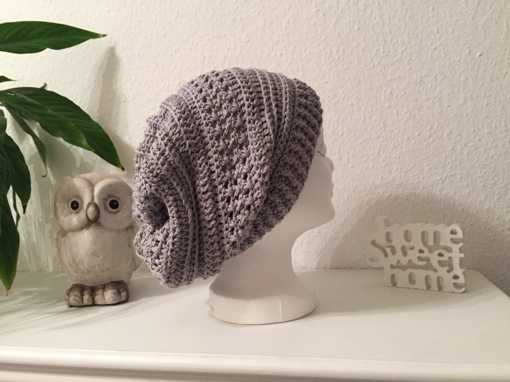 Gehäkelte graue Slouchy-Beanie auf Schaufensterkopf mit offenem Maschenbild und geripptem Rand