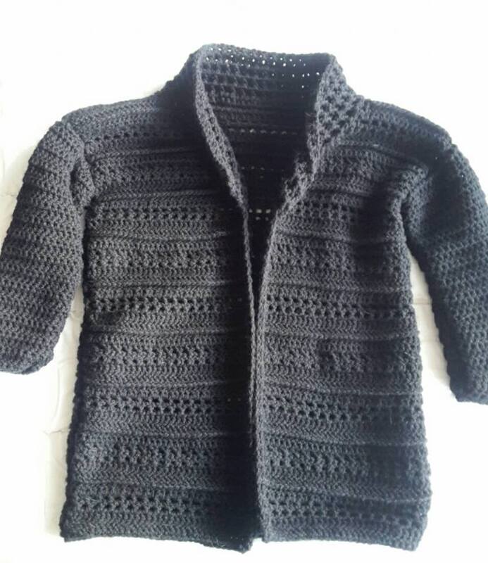 Schwarze gehäkelte Jacke mit Stehkragen und langen Ärmeln, auf hellem Untergrund