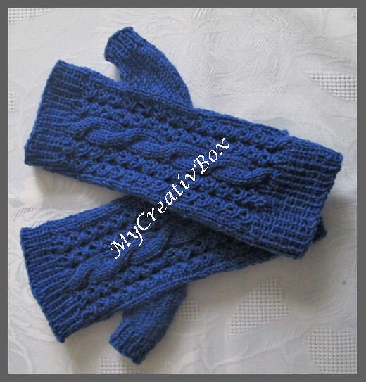 Dunkelblaue gestrickte Armstulpen mit Zopfmuster und Daumenloch, flach liegend.