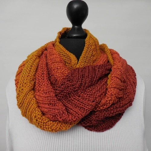 Gestrickter Loop-Schal in Senfgelb, Orange und Rostrot auf schwarzer Schaufensterpuppe