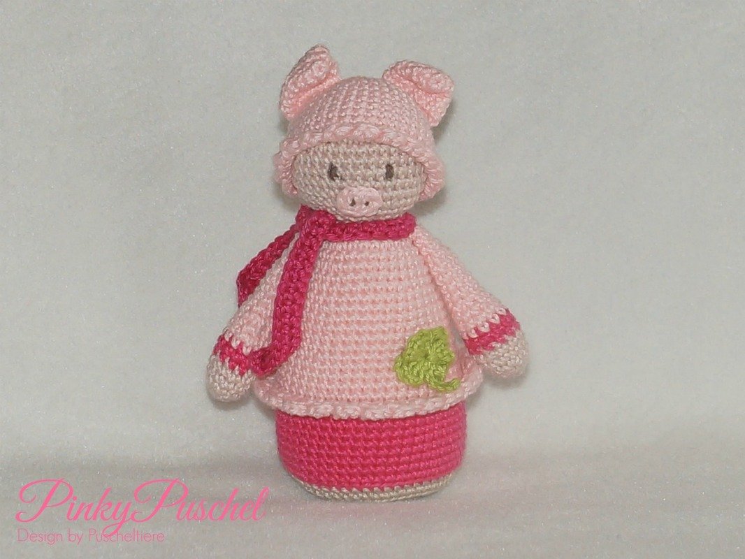 Rosa gehäkeltes Amigurumi‑Schweinchen mit Mütze, Schal und grünem Kleeblatt