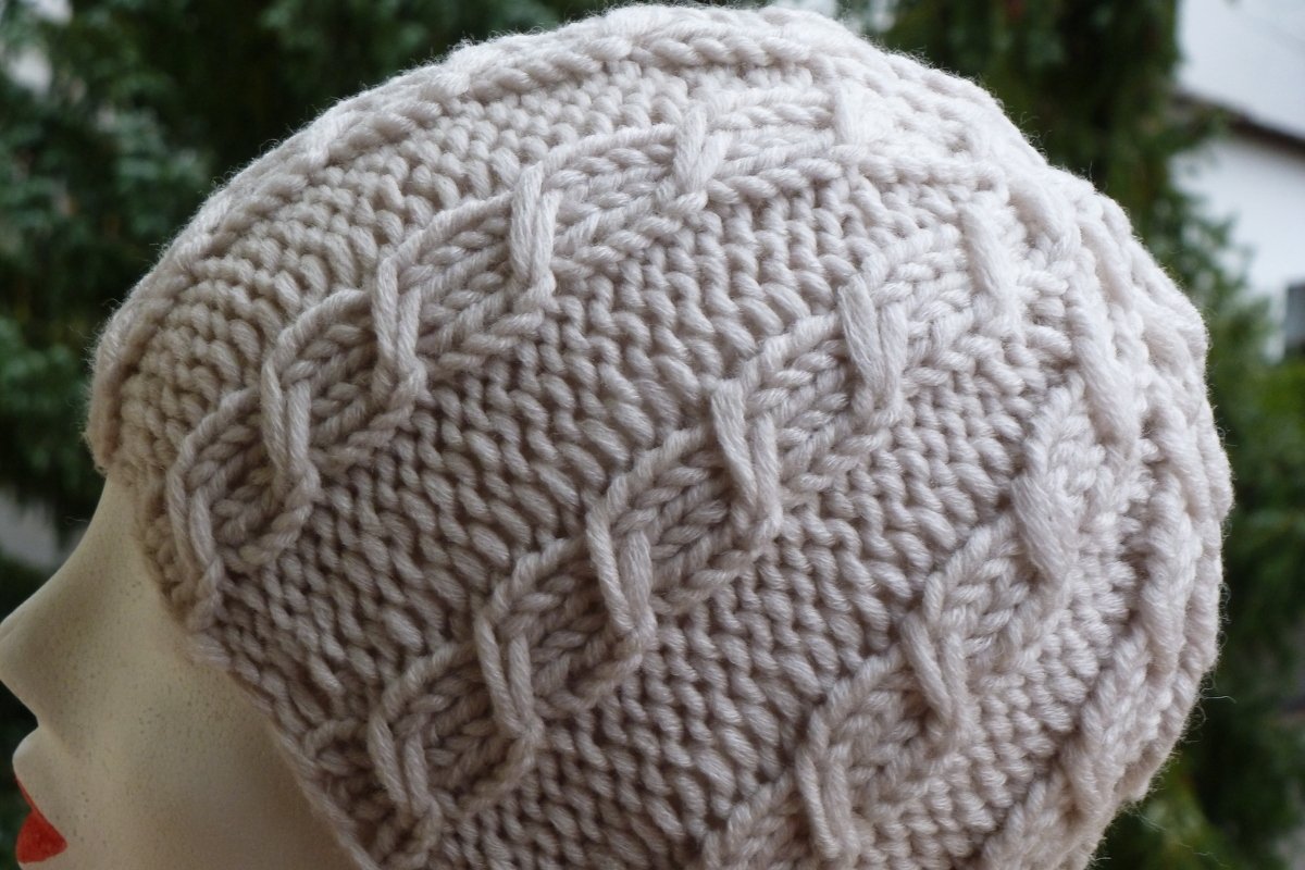 Hellbeige gestrickte Mütze mit Zopfmuster auf Schaufensterkopf