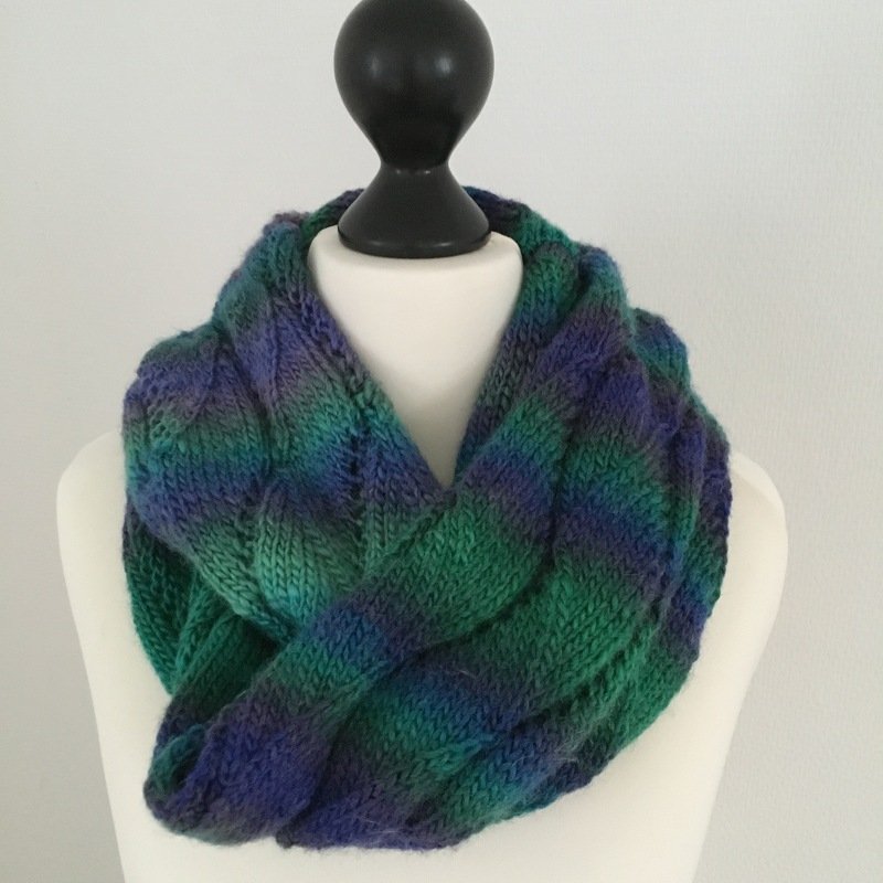 Mehrfarbiger Loop‑Schal mit Zopfmuster auf einer Schaufensterbüste