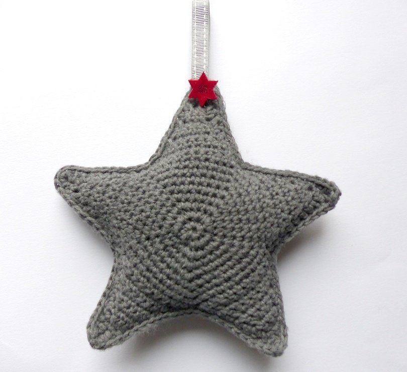 Gehäkelter grauer Sternanhänger mit Band und kleinem roten Zierstern