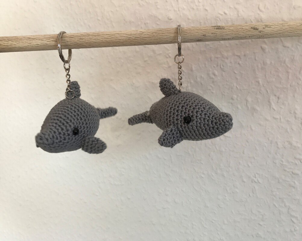 Zwei kleine graue gehäkelte Delfin-Schlüsselanhänger an Metallringen