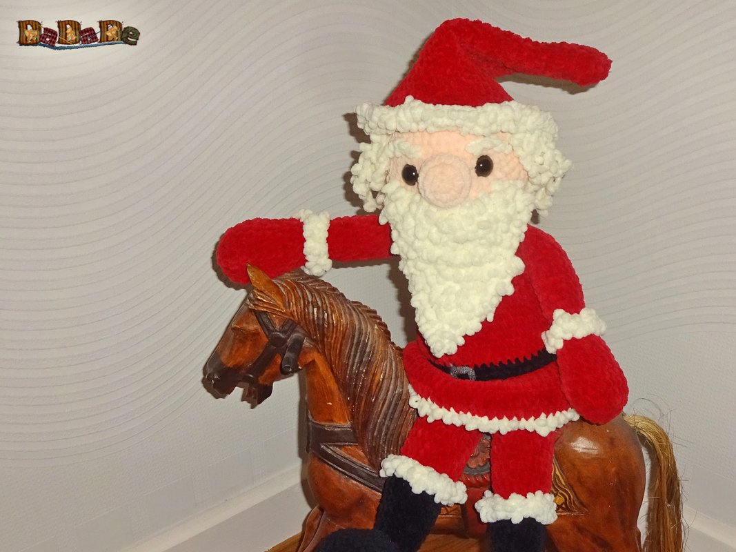 Nahaufnahme gehäkelter Weihnachtsmann auf Holzschaukelpferd