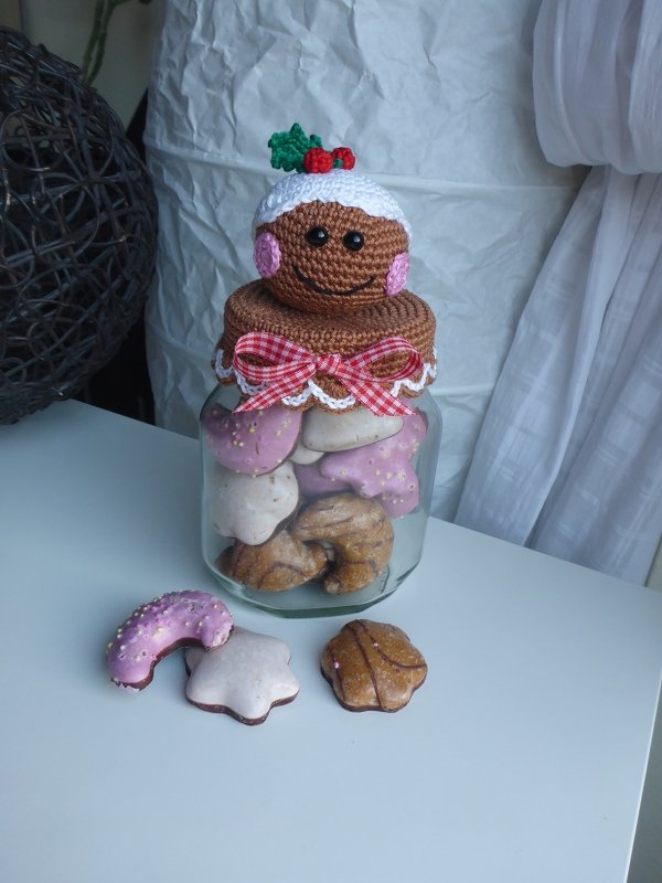 Glas mit Weihnachtskeksen und gehäkeltem Lebkuchen-Deckel mit roter Schleife