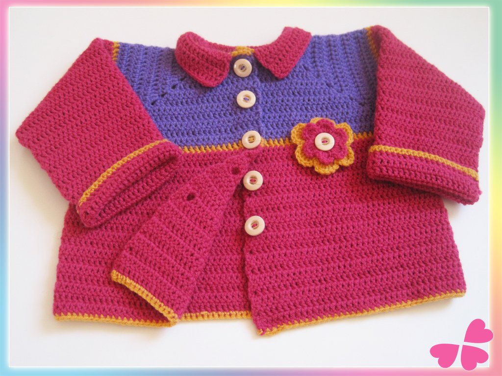 Gehäkelte Babyjacke pink und lila mit gelber Zierkante, Knopfleiste und Blumen-Applikation, liegend