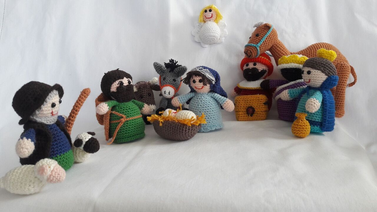 Gehäkelte Krippenszene mit mehreren Amigurumi-Figuren auf weißem Hintergrund